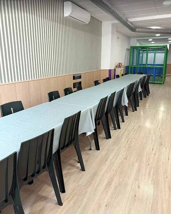 Mesas largas para invitados junto a la zona de juegos