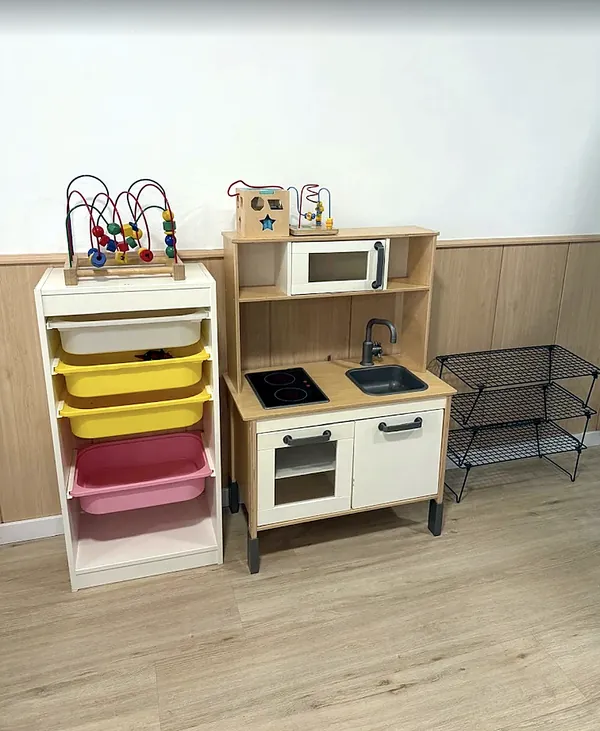 Rincón de juego con cocinita de madera y juguetes